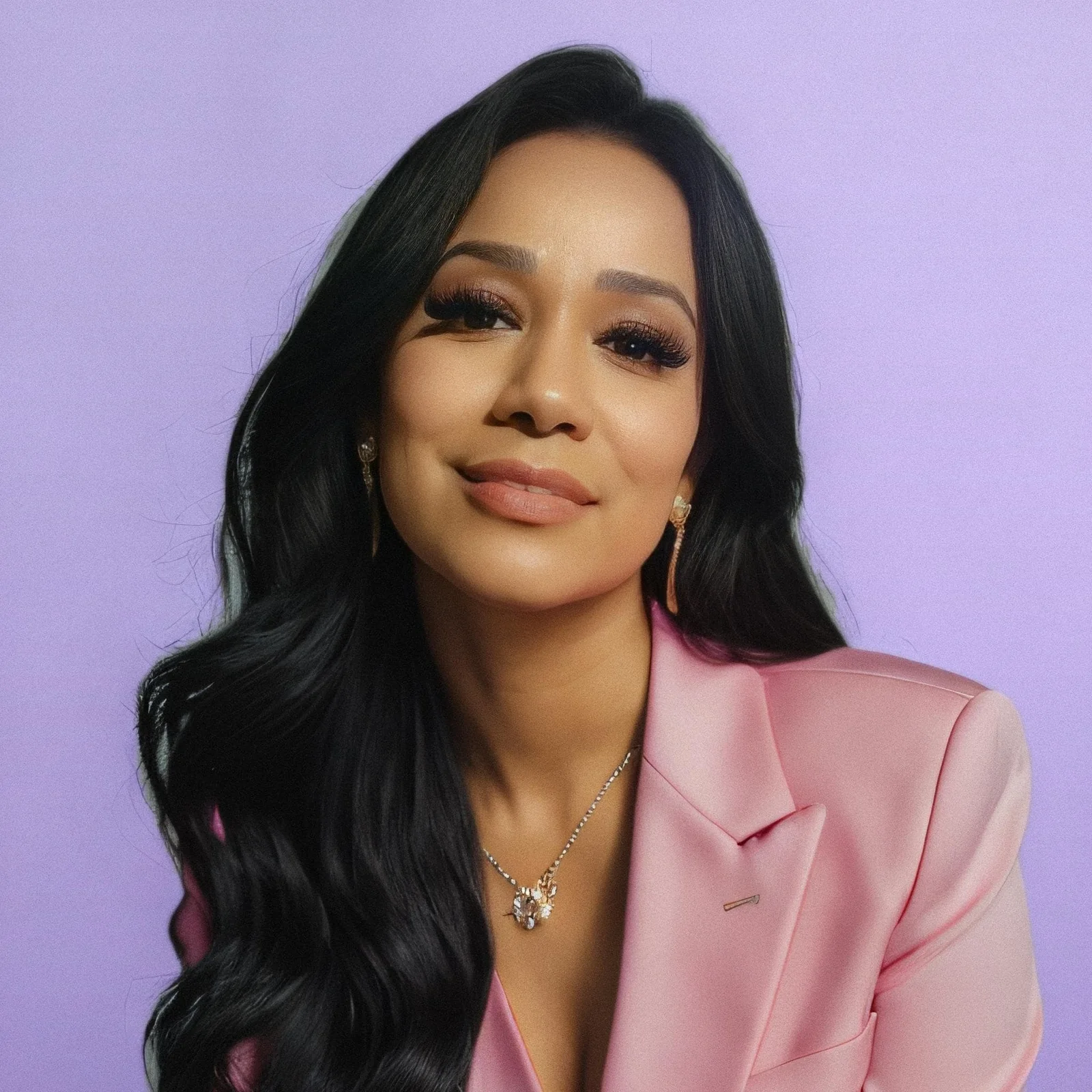 Cláudia Martins smiling in a pink blazer, with long dark hair and her own lash extensions